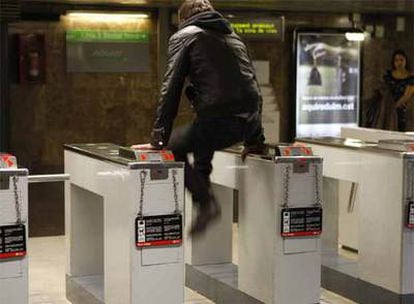 Un muchacho entra sin pagar en el metro en una estación con videocámaras.