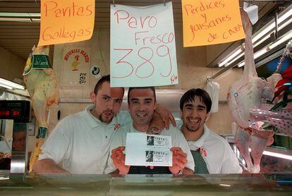 Tres trabajadores de una pollería de una galería comercial del barrio del Pilar de Madrid, muestran fotocopias de dos décimos del número 17.913, agraciado con el segundo premio de la Lotería navideña de 1999. 