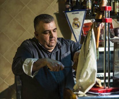 Gregorio Pifarre, dueño del Casal d'Alfés, el único restaurante el pueblo, corta una loncha de jamón. De fondo, el banderín del Real Madrid.