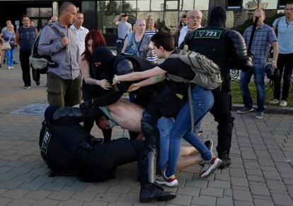 Dos antidisturbios detienen a un manifestante mientras dos mujeres le defienden, el 10 de agosto en Minsk. 