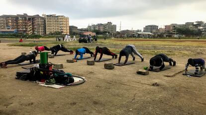 Media docena de miembros del 'Team Tina' hace flexiones en el espacio al aire libre habilitado como gimnasio en el barrio de Tena, en Nairobi, Kenia.