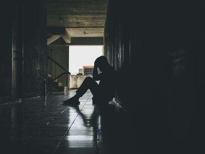 Un chico sentado en el suelo, con las manos en la cabeza, en actitud triste, en una foto de archivo.
