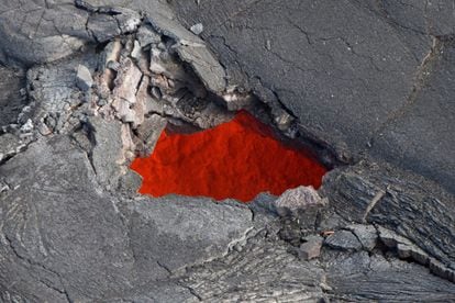 La ruptura del techo de un tubo de lava activo crea una claraboya que permite una mirada al interior del conducto, que lleva lava fundida al frente de flujo. El río de lava continúa ampliándose llegando cerca de las propiedades de Kaohe, 30 de octubre de 2014.