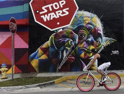 Una joven cruza junto a un grafiti del artista brasileño Kobra en el distrito Wynwood.