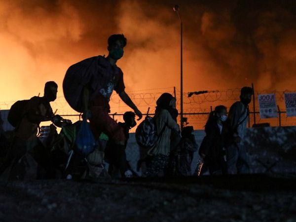 Refugees and migrants carry their belongings as they flee from a fire burning at the Moria camp, on the island of Lesbos, Greece, September 9, 2020. REUTERS/Elias Marcou
