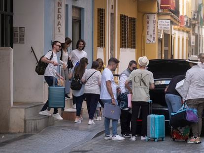 Varios jóvenes cargados con maletas salen de un piso turístico en Sevilla, el pasado abril.