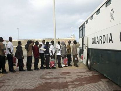 Un grupo de inmigrantes subsaharianos hace cola para subir a un autob&uacute;s de la Guardia Civil en Tarifa para ser trasladado a C&aacute;diz.