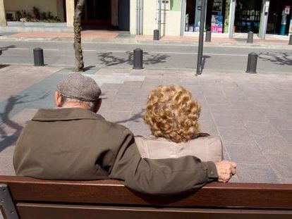 Una pareja de ancianos toma el sol en un banco.