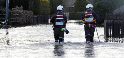 Miembros de los servicios de emergencia caminan este viernes por las calles inundadas de Moorland (Reino Unido).