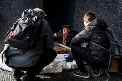 Una persona sin hogar atiende a dos educadores de Arrels, en una imagen de archivo.