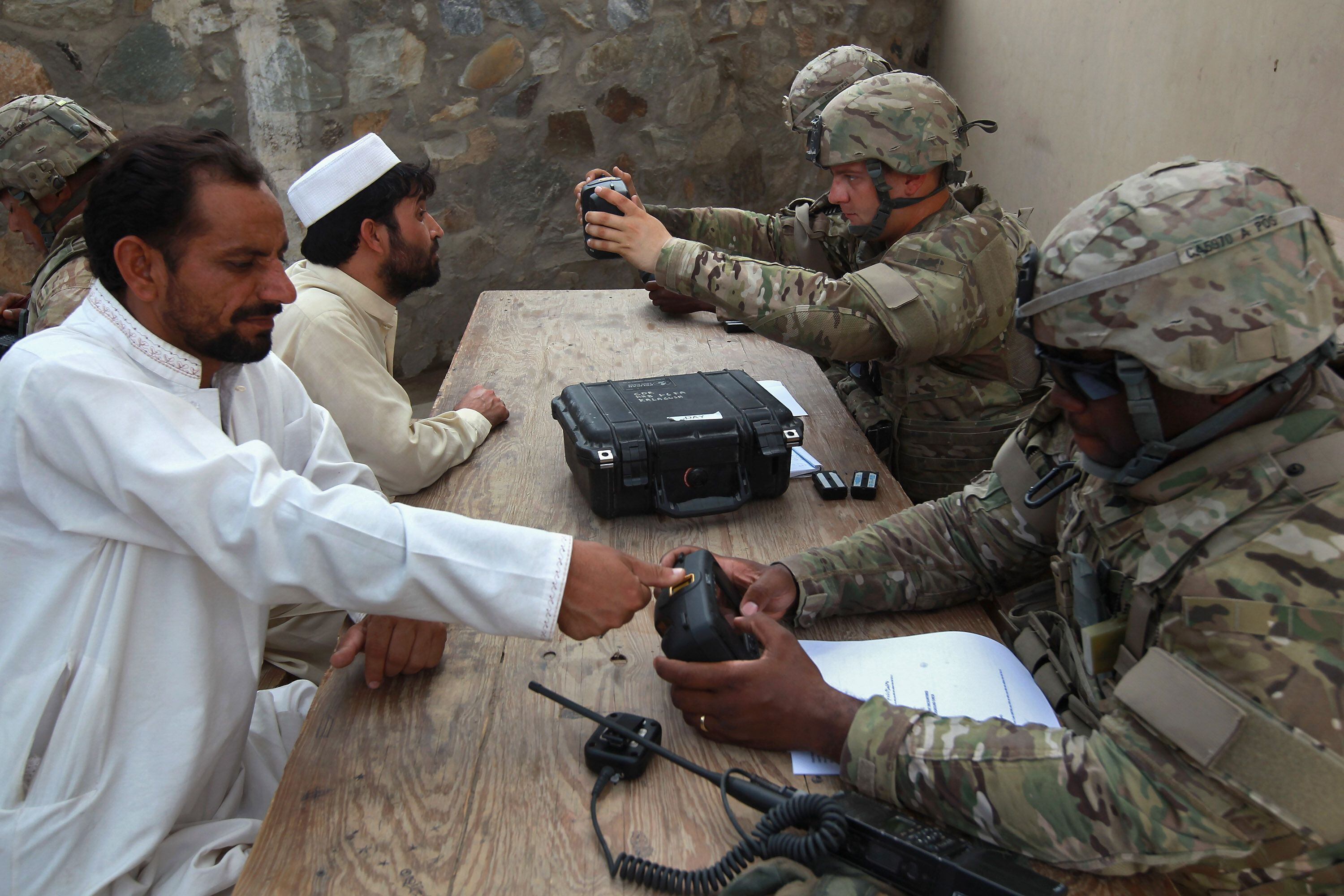 Soldados estadounidenses registran la huella dactilar y el iris de dos hombres que entran a Afganistán desde Pakistán.