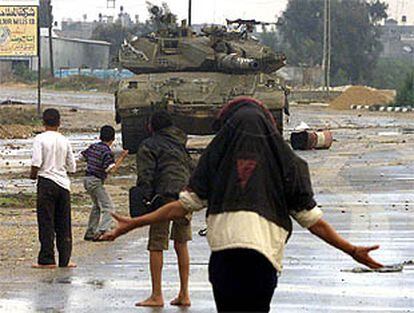 Jóvenes palestinos se enfrentan lanzando piedras a los tanques del Ejército israelí.