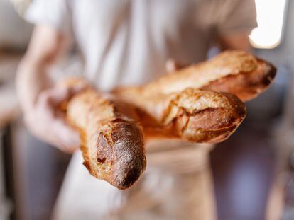 Un panadero sostiene tres barras de pan en París, Francia.