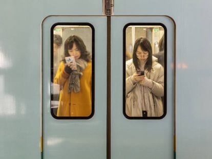 Dos mujeres consultan sus teléfonos móviles mientras viajan en el metro de la ciudad de Chongqing (China). 