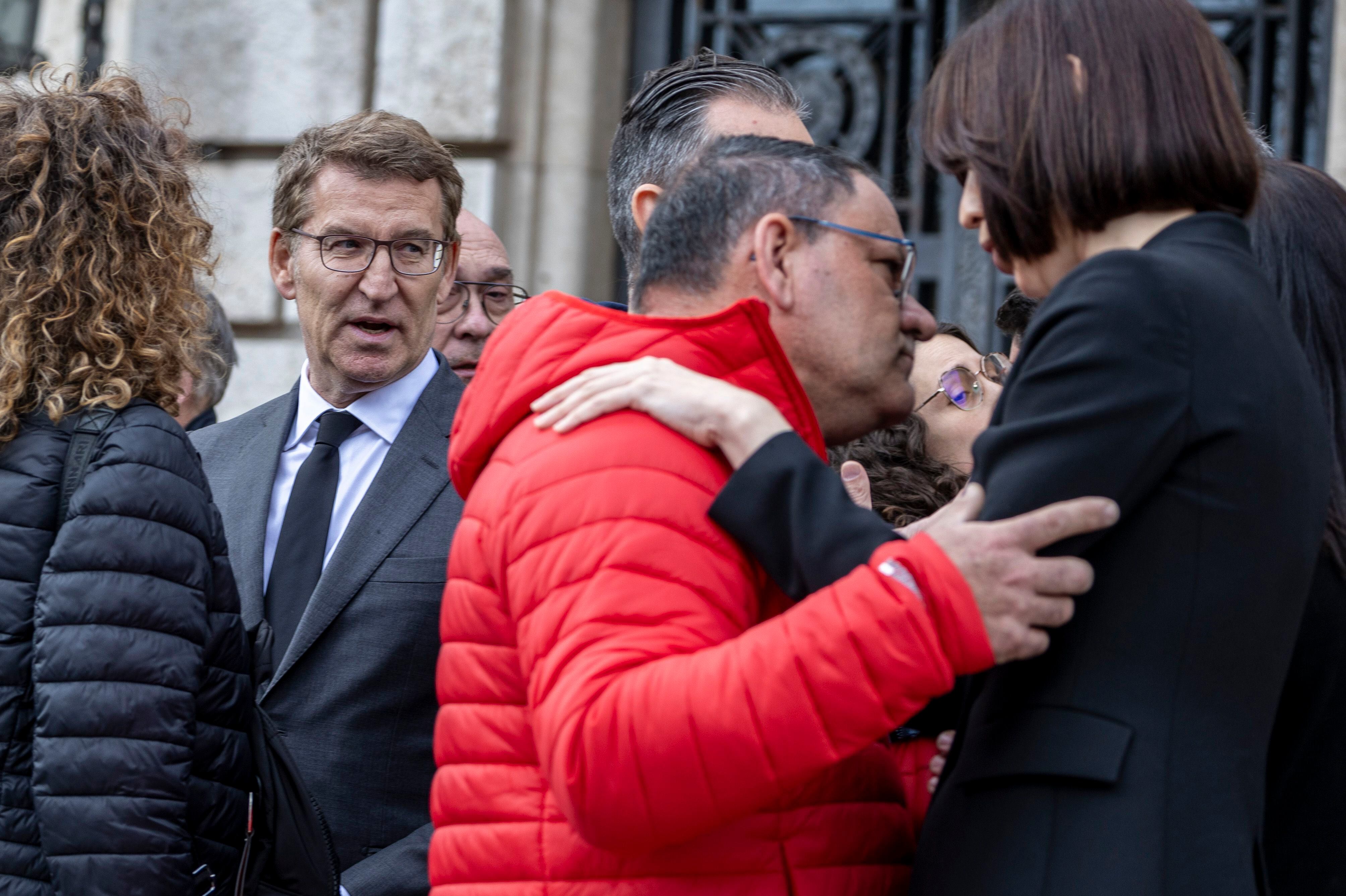 La ministra de Ciencia, Diana Morat (a la derecha), saluda al conserje del edificio calcinado, Julian, ante el líder del PP, Alberto Núñez Feijóo, tras el ministro de silencio frente al Ayuntamiento. 