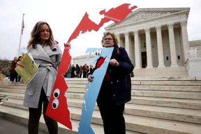 Dos personas con el trazado de mapas electorales protestan el miércoles frente al Tribunal Supremo, en Washington