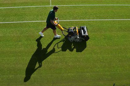 Un trabajador corta el césped de una de las pistas de tenis de Wimbledon, Londres.