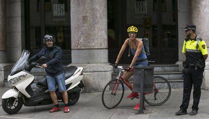 Un motorista, una ciclista y un policía en la Via Laietana