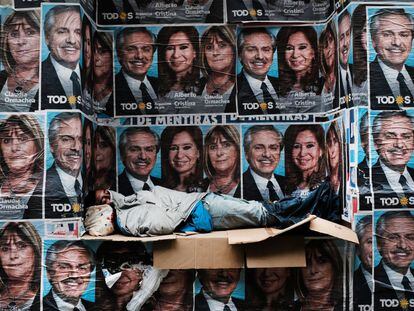 Un hombre sin hogar duerme debajo de los carteles que muestran al presidente, Alberto Fernandez, y su vice, Cristina Kirchner, el día después del triunfo del peronismo en las elecciones de 2019.