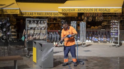 Un trabajador de la contrata municipal limpia unas papelera este martes en una calle del centro de Valencia.