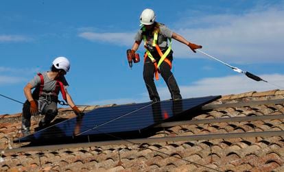 Dos operarios trabajan en la instalación de placas solares en el tejado de una casa, esta semana en Avinyó (Barcelona).