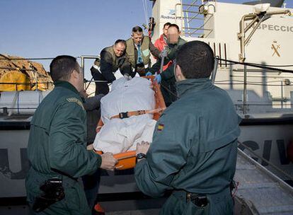 Miembros de la Guardia Civil trasladan en el puerto de Almería el cuerpo del muerto en la travesía de una patera en la que viajaban 36 inmigrantes.