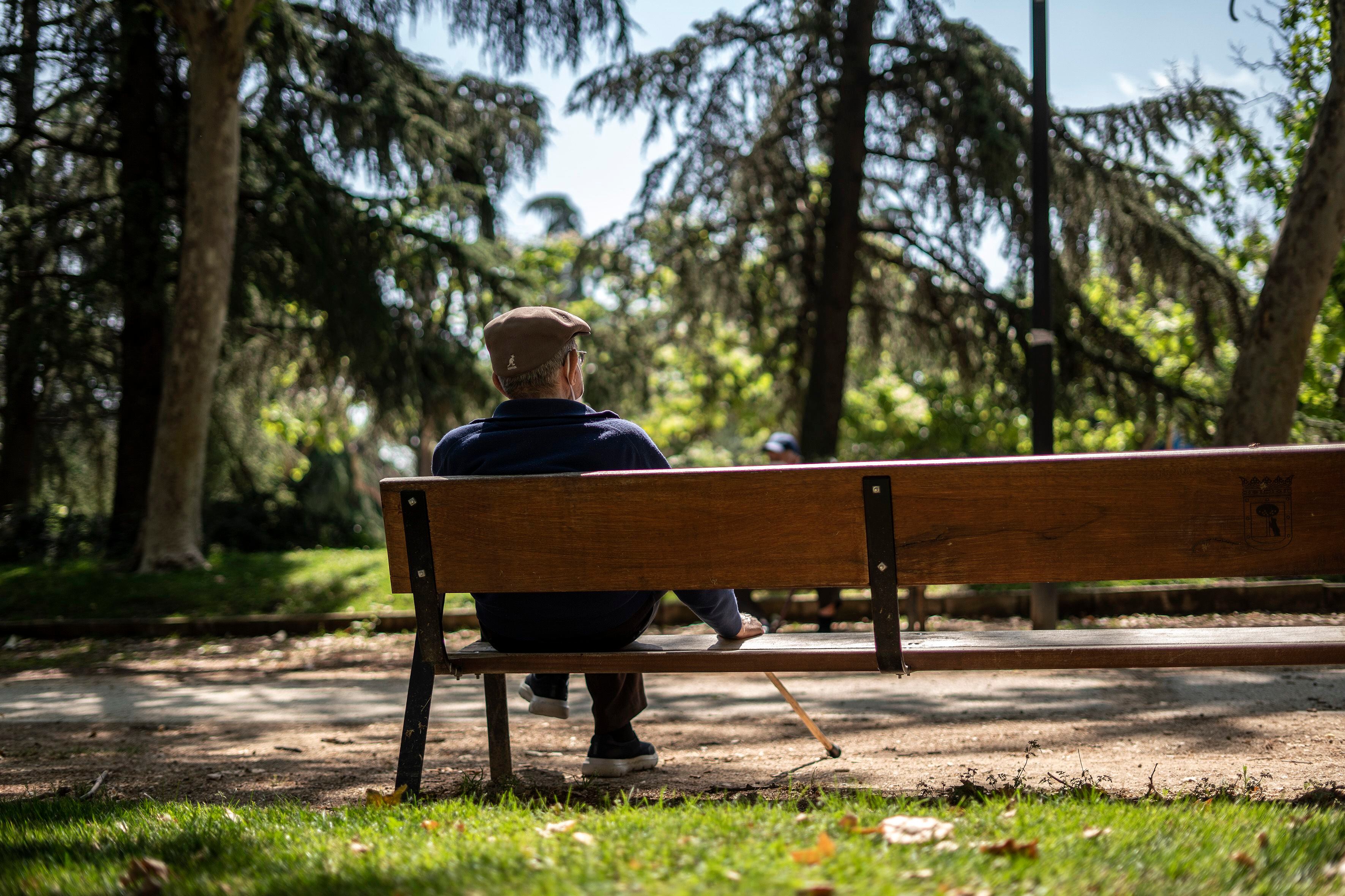 Un hombre sentado solo en un banco del parque Caramuel, en el barrio de Puerta del Ángel, Madrid.