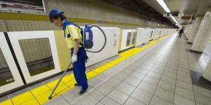 Un operario limpia el suelo del andén de una estación de metro de Tokio.