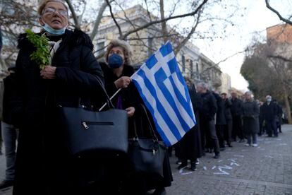 Una mujer sostiene una bandera griega mientras espera para dar el último adiós al exrey en la capilla San Eleftherios antes del funeral. 
