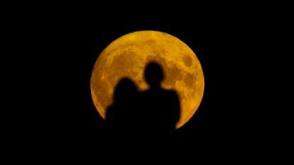Dos personas miran la superluna salir en Londres (Reino Unido), este jueves.