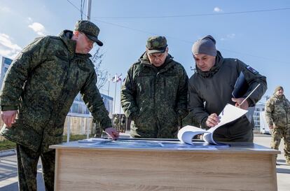 Serguéi Shoigú (en el centro) inspecciona uno de los planos de reconstrucción, esta luna en Mariupol.