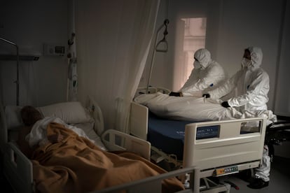 Unos operarios envuelven el cadáver de una persona en una residencia de Barcelona el pasado 5 de noviembre.