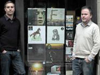 Los propietarios de la tienda de música CD Drome, Oriol Valls (izda.) y Jordi Raich (dcha.), posan ante el escaparate de su local