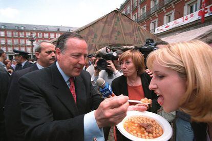 El alcalde José María Álvarez del Manzano da a probar de un plato en el tradicional cocido madrileño en la plaza Mayor de Madrid, organizado en beneficio de Aldeas Infantiles SOS, cuya preparación corrió a cargo de militares de la Agrupación de Abastecimiento I-11 del Ejército de Tierra el 20 de mayo de 2001.