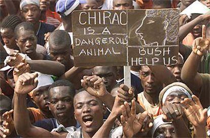 Manifestantes contra el acuerdo de paz muestran pancartas que califican a Chirac de "animal peligroso" y que piden ayuda a Bush, ayer en Abiyán.