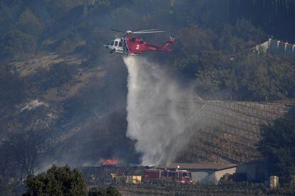 Un helic&oacute;ptero de los bomberos apaga el fuego que afecta al vi&ntilde;edo propiedad de Rupert Murdoch en el barrio de Bel Air, en California.