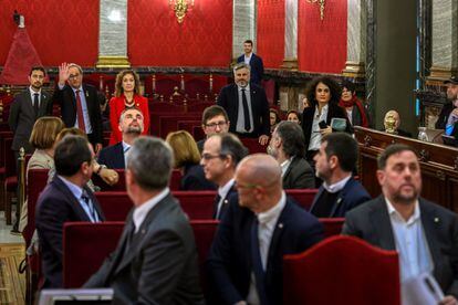 El presidente de la Generalitat, Quim Torra (al fondo, segundo por la izquierda), saluda a los 12 líderes independentistas acusados por el proceso soberanista catalán que derivó en la celebración del 1-O y la declaración unilateral de independencia de Cataluña, en el banquillo del Tribunal Supremo, al inicio del juicio del 'procés', el 21 de febrero.