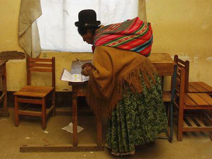 Una indígena boliviana marca la papeleta de votación del referéndum constitucional en un colegio electoral en El Alto (La paz)