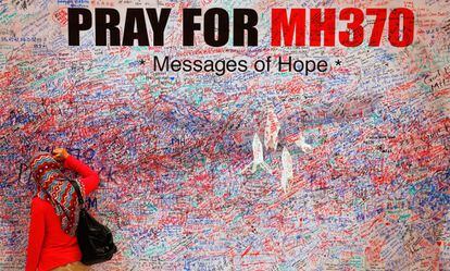 Una mujer escribe un mensaje en un mural en recuerdo de las víctimas del vuelo MH370, en el centro de Kuala Lumpur en marzo de 2014.