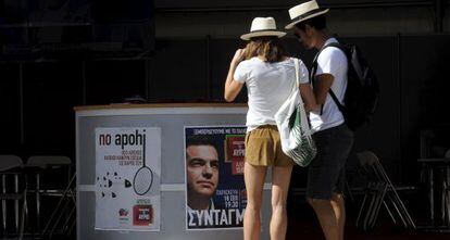 Touristas frente a un puesto electoral de Syriza, hoy en Atenas