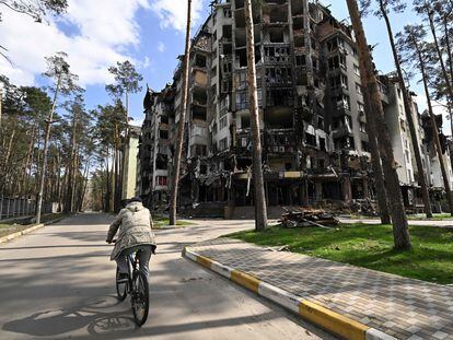 Un hombre en bici pasa junto a un edificio residencial destruido en Irpin, al noroeste de Kiev, el pasado 24 de abril.