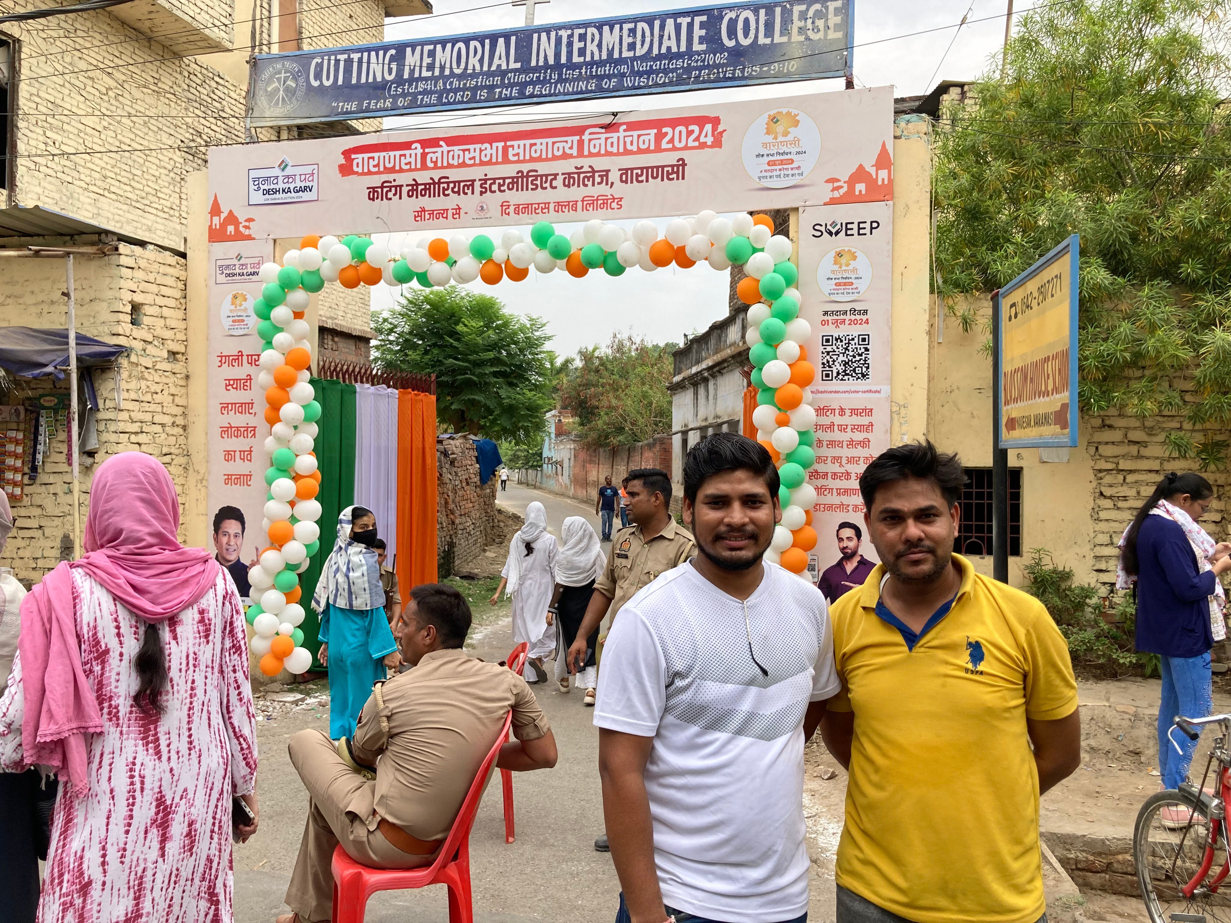 Amigos Rahul Chaudhary e Mohamed Nadeen, que votam em opções políticas opostas, no portão de uma seção eleitoral em Varanasi, no sábado, 1º de junho. 