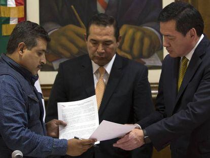 El secretario de Gobernación, a la derecha, intercambia documentos con un representante de la CNTE.
