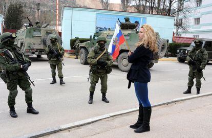 Un mujer prorrusa ondea una bandera frente a hombres armados sin identificar en el puesto fronterizo de la ciudad de Balaklava, en Crimea.  
