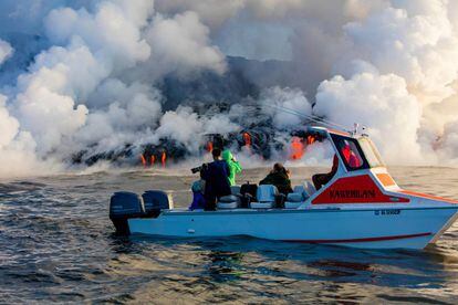 Una lancha turística se aproxima al volcán Kilauea para observar sus ríos de lava.