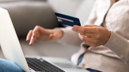 Close up woman shopping, paying by credit card, buying goods or ordering online, using laptop, login internet bank service, typing on keyboard, checking balance, sitting on sofa at home