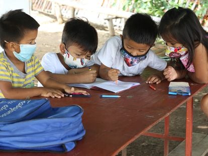 Cuatro alumnos hacen sus deberes al aire libre en una de las clases que se imparten de manera informal en un barrio de Guayaquil.