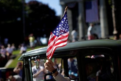Un hombre ondea una bandera estadounidense mientras conduce un coche antiguo a través de Barnstable Village, en Cape Cod durante las celebraciones anuales desfile Día de la Independencia, Massachusetts.