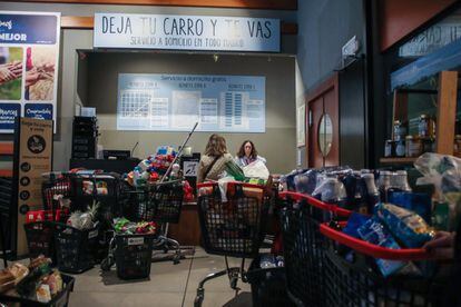 Dos clientas de un supermercado del centro de Madrid entregan sus compras para su posterior entrega a domicilio.