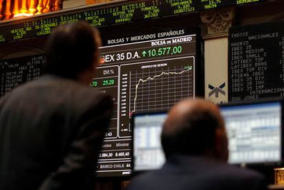 Un grupo de inversores observa el panel que muestra la subida del Ibex, ayer en la Bolsa de Madrid.